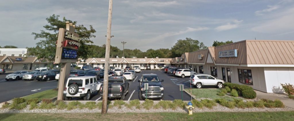 The office from Indianapolis Boulevard: a one-story strip of offices with a brown metal roof and parking in front